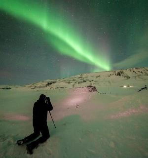 a person on skis in the snow under the northern lights