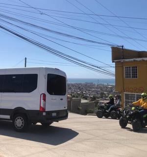 una furgoneta i dues persones en motocicletes al costat d'un edifici