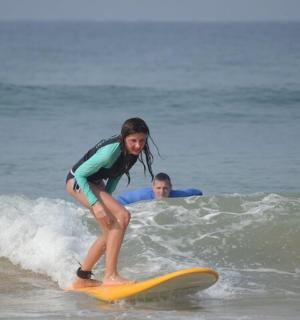 a young girl riding a wave on a surfboard in the ocean