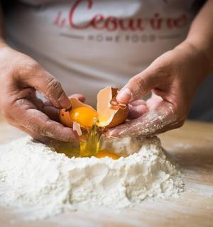 一个人在桌子上把鸡蛋切进面粉里