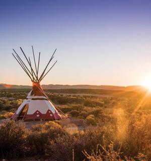 沙漠中一座红白相间的帐篷，夕阳西下