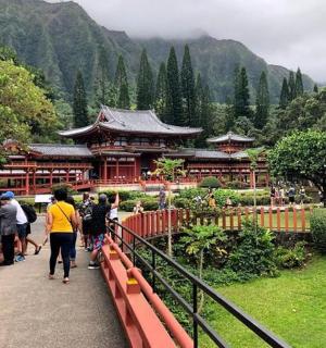 skupina lidí jdoucích po mostě před budovou