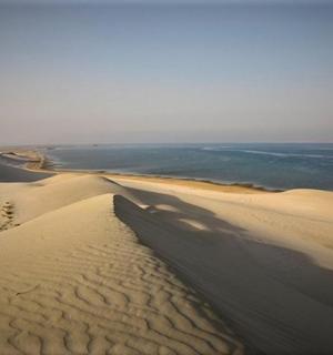 a view of a desert with the ocean in the background