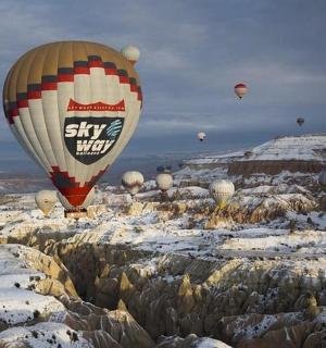 一群热气球飞过白雪覆盖的岩石