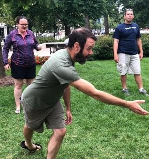 a man throwing a frisbee in a park with two women