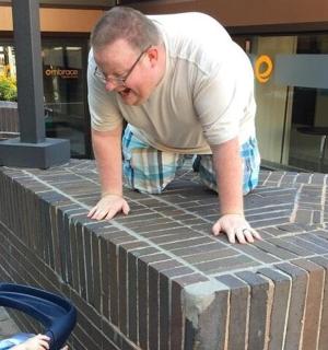 muž dívající se na dítě na cihlové zdi