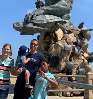 a family posing in front of a dinosaur statue