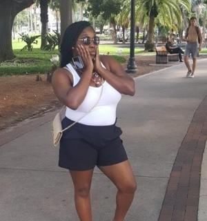 一位身穿白衬衫和短裤的女士正在打电话