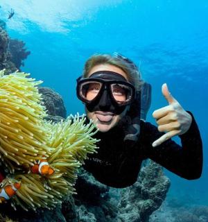 a man giving a thumbs up next to a fish in the ocean
