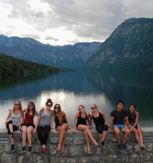 skupina žen sedících na zdi poblíž jezera