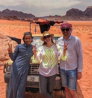 三个人站在沙漠中的一辆卡车前