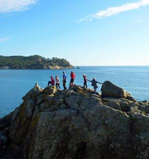 a group of people standing on a rock formation on the ocean