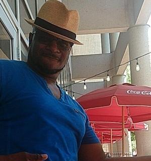 a man wearing a hat standing next to a red umbrella