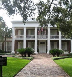 velký bílý dům s cedulí před ním