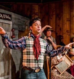 muž stojící na pódiu s rozpaženýma rukama