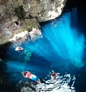 un grup de persones nedant a l'aigua prop d'una cova