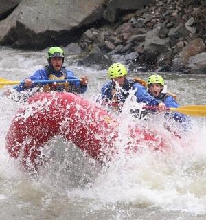 three people in a raft in a river