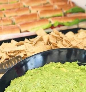 一碗鳄梨酱和薯条，旁边是一盘三明治