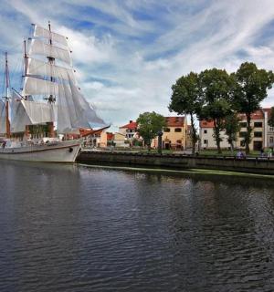 a sail boat is docked in a river next to buildings
