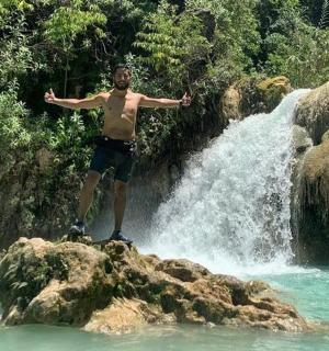 muž stojící na skále před vodopádem