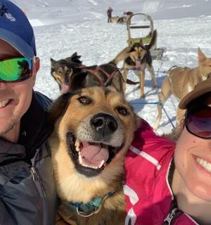 a man and a woman and a dog in the snow