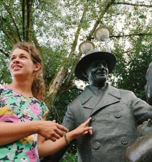 a woman standing next to a statue of a man