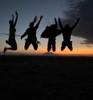 a group of people jumping in the air at sunset