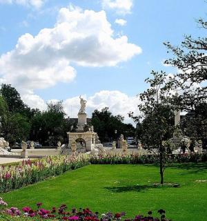 a park with a statue in the middle of a park with flowers