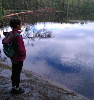 osoba z plecakiem stojąca obok jeziora