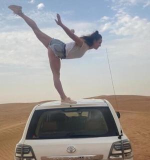 a woman standing on the roof of a car in the desert