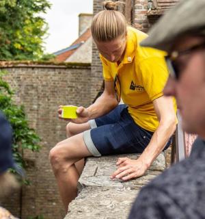 一名男子坐在墙上，手里拿着一个黄色的杯子