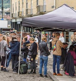 ฝูงชนยืนอยู่ใต้เต็นท์พร้อมกับม้า