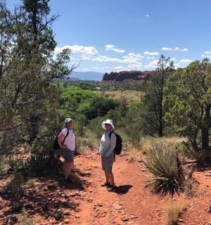 dva lidé jdoucí po prašné stezce v poušti