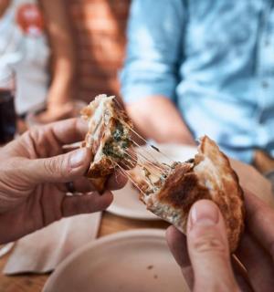 eine Gruppe von Menschen, die ein Stück Pizza essen