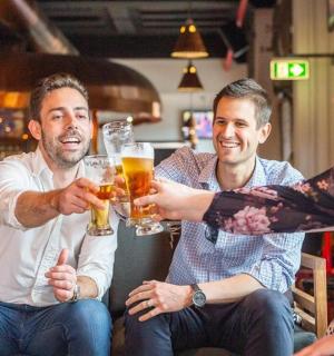 two men and a woman holding glasses of beer