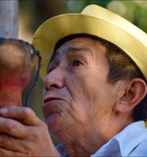 一位戴着帽子、手里拿着木制物品的老人