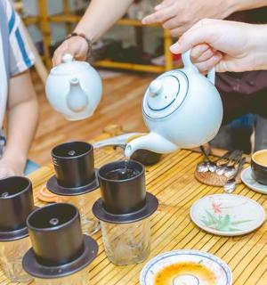 一群人围着桌子站着,手里拿着茶壶