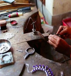 a person cutting a piece of metal on a table
