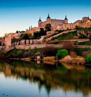 a castle on a hill next to a river with a bridge