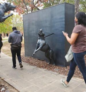 skupina lidí procházejících kolem sochy psa