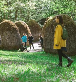 a woman walking in front of a group of hay spheres