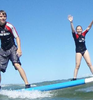 a man and a woman on a surfboard in the ocean