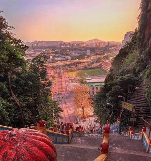 osoba s červeným deštníkem shlížející z hory