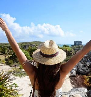 一位戴着帽子的女人坐在沙滩上,双臂高举