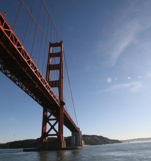a bridge over the water with the sun behind it