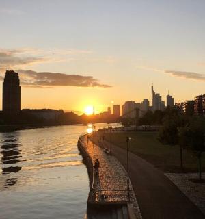 ein Sonnenuntergang über einem Fluss mit einer Stadt im Hintergrund