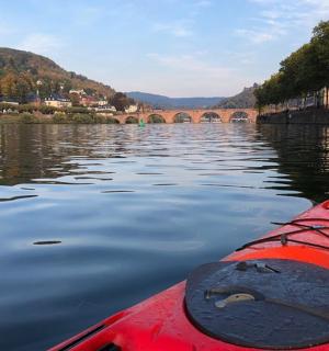 a red kayak on a river with a bridge
