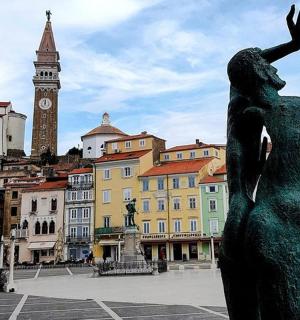 socha ženy ve městě s hodinovou věží