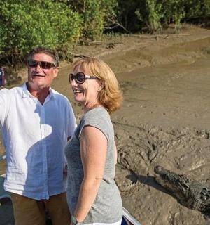 a man and woman taking a picture of an alligator