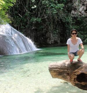 a woman sitting on a log in front of a waterfall